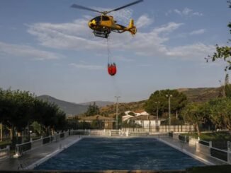 Um helicóptero de bombeiro coleta água de uma piscina para combater um incêndio florestal Pablo Blazquez Dominguez/Getty Images