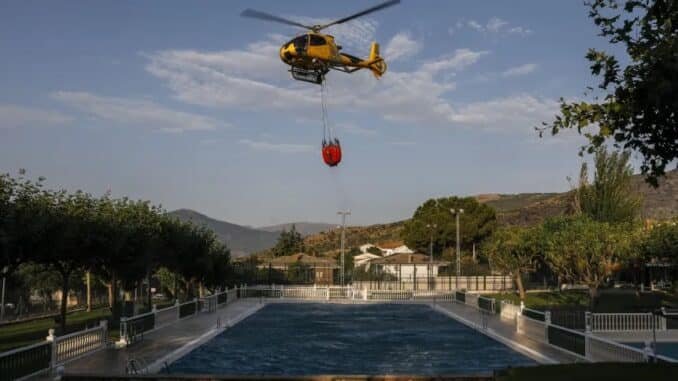 Um helicóptero de bombeiro coleta água de uma piscina para combater um incêndio florestal Pablo Blazquez Dominguez/Getty Images